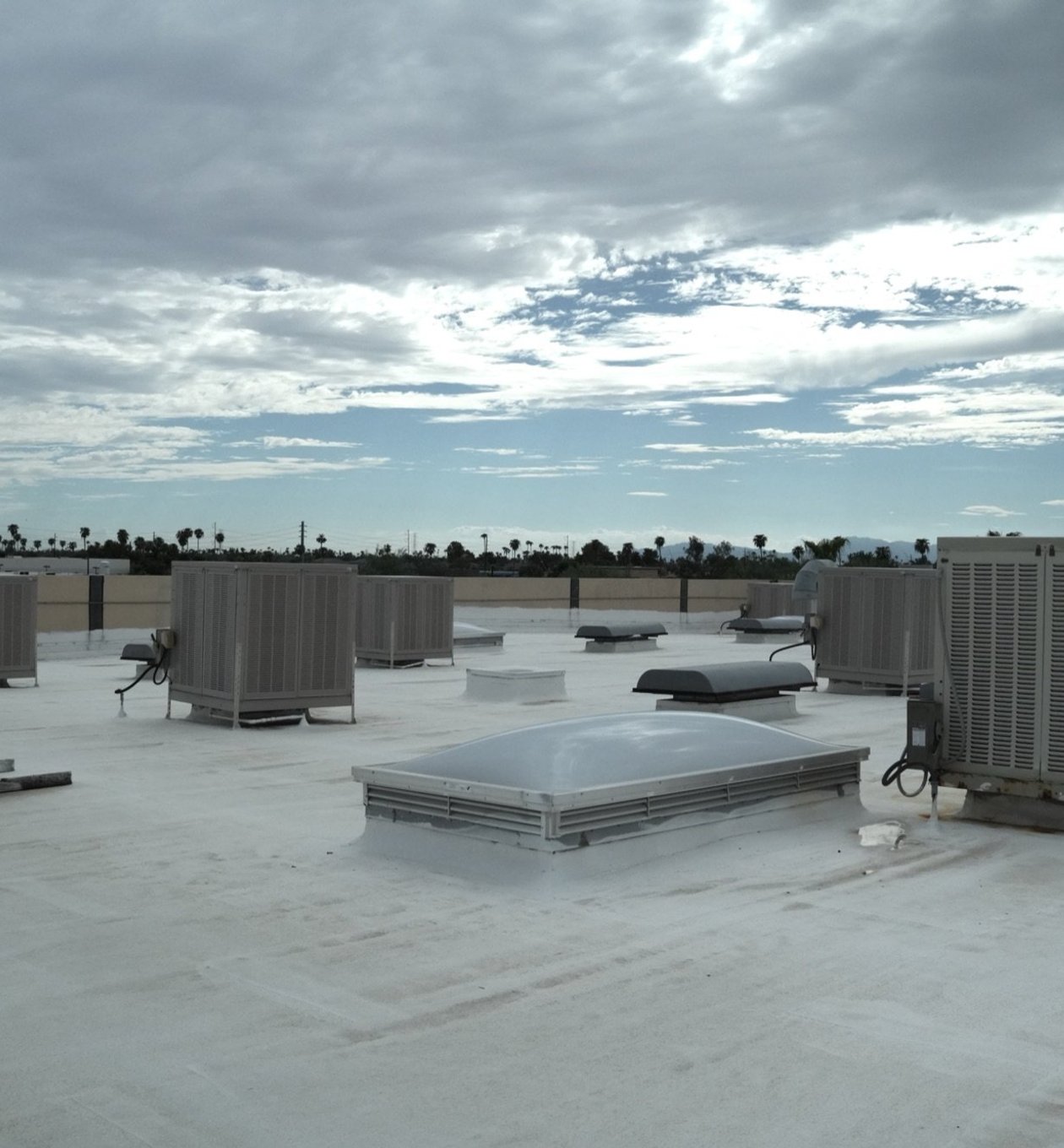 Rooftop units and swamp coolers across a commercial roof