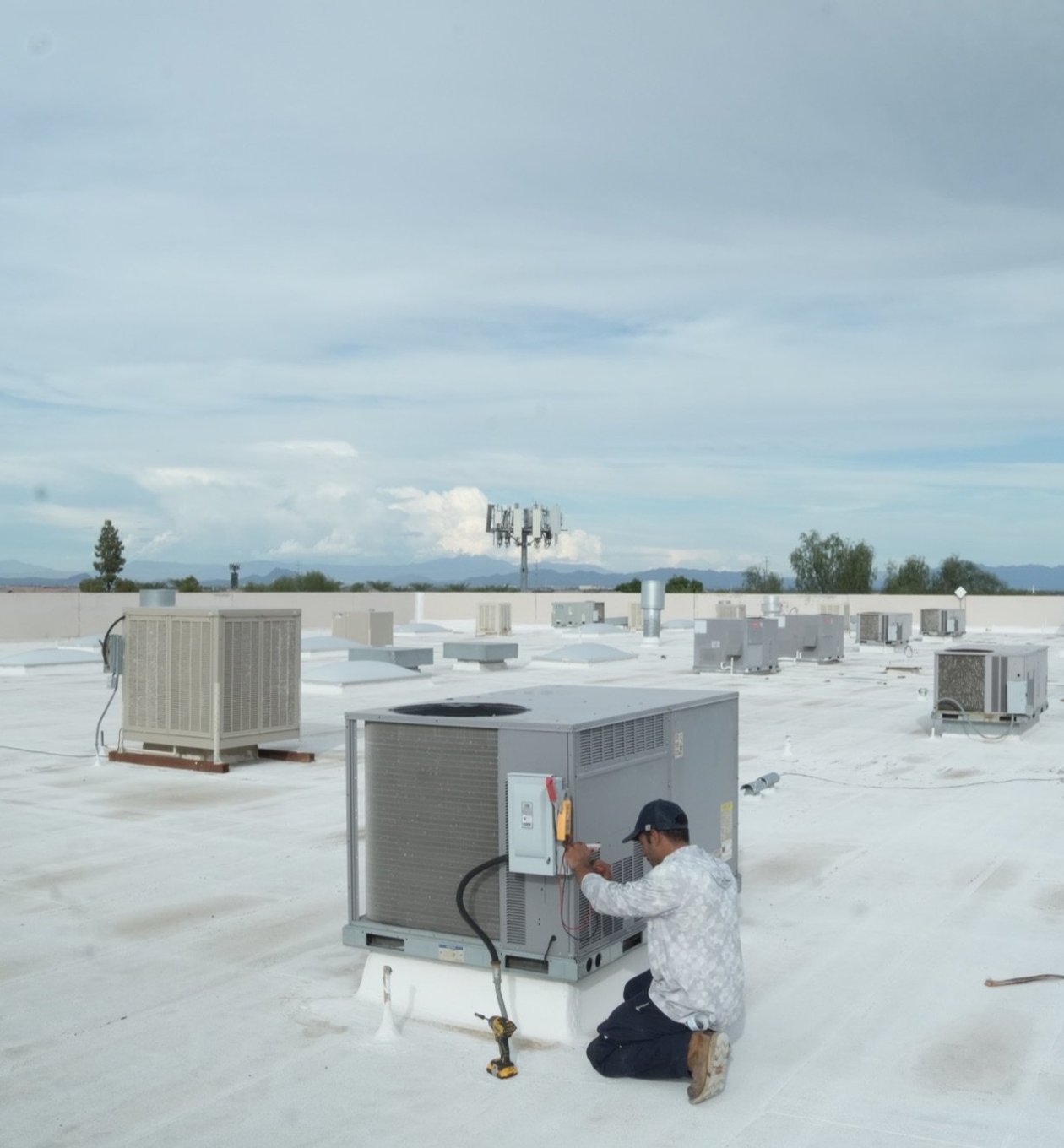 Due-All technician servicing a rooftop package unit on a commercial roof