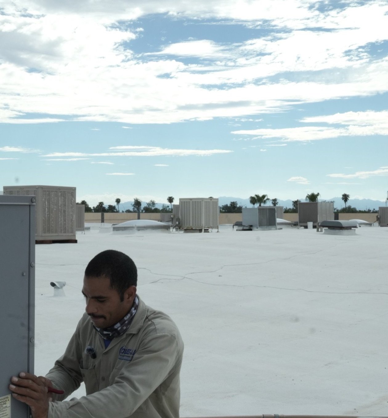 Due-All technician servicing a commercial rooftop unit with the panel open